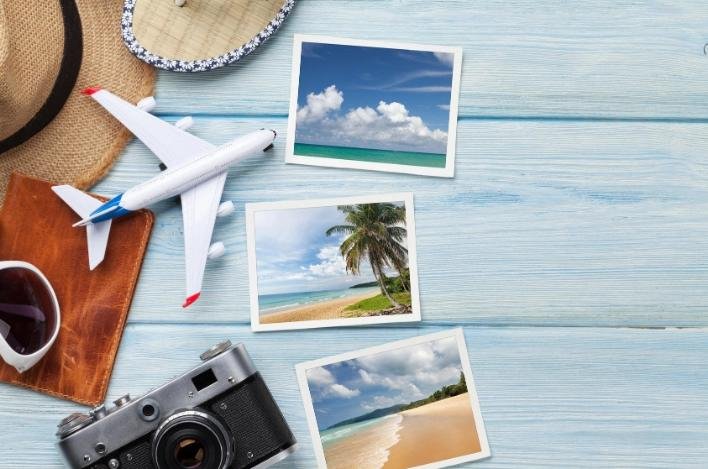 Vacation photos, a miniature plane, sun hats and camera on a table